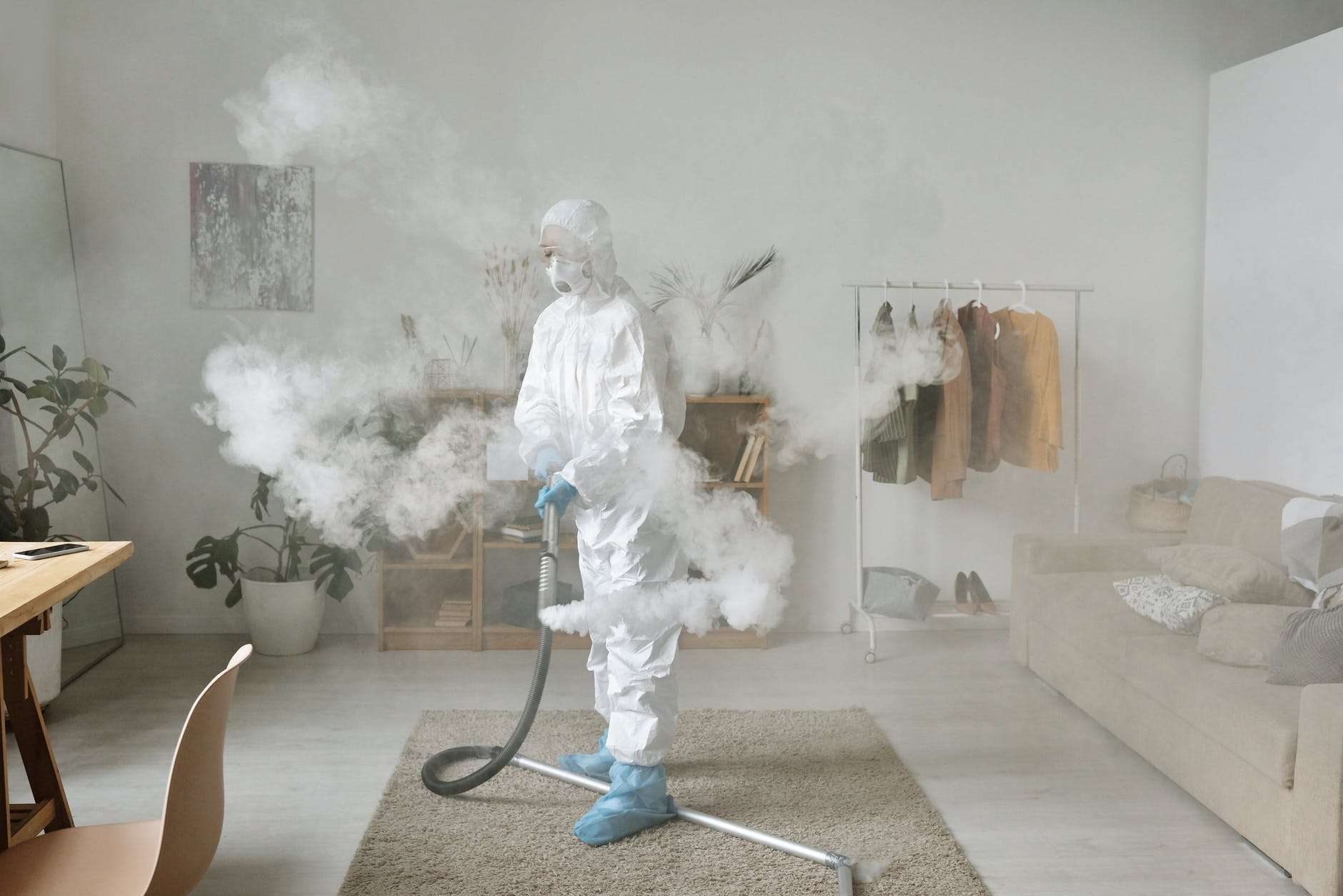 a person disinfecting while wearing a protective suit